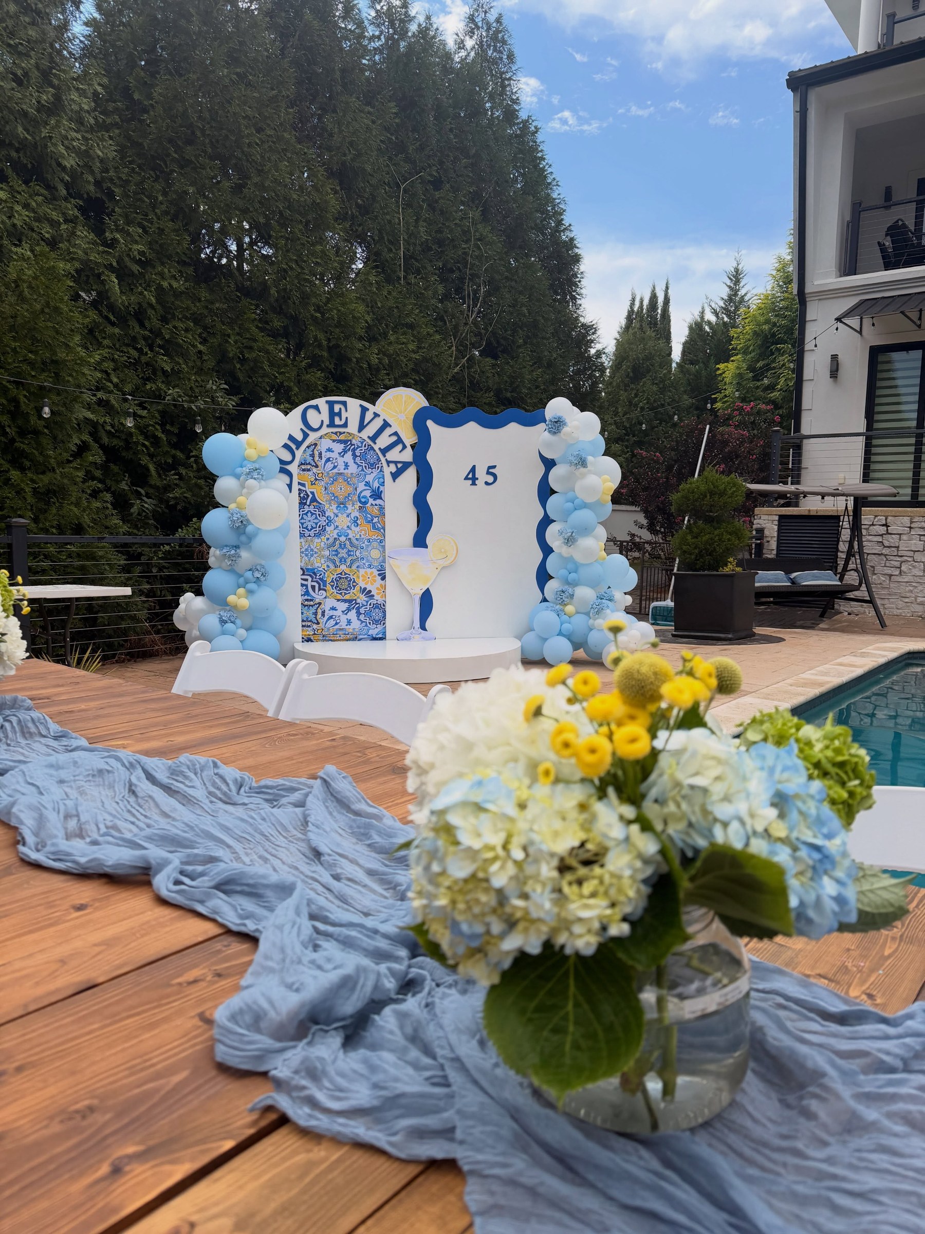 Celebración Dolce Vita con globos azules, limones y flores junto a una piscina